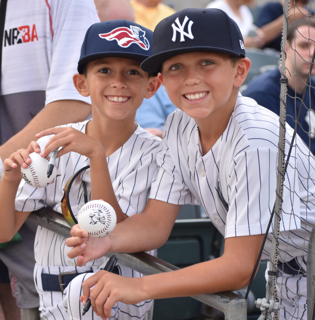 kids holding baseball dressed in uniform