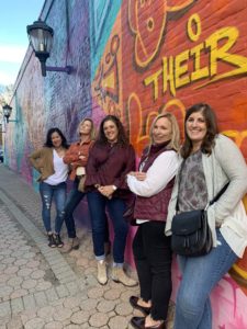 women standing in front of mural