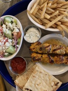 plate with chicken skewers fries pita salad