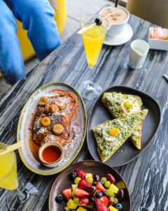 brunch spread with avocado toast pancakes and fruit